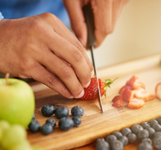 Close-up of hands cutting up a strawberry on a cutting board