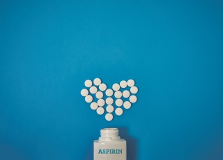 Aspirin bottle on its side, with aspirin tablets forming a valentine heart shape