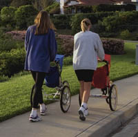 Two mothers walking with jogging strollers