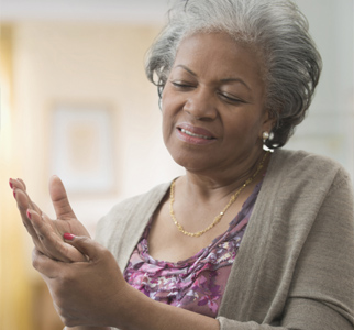Older woman feeling her hand, in pain