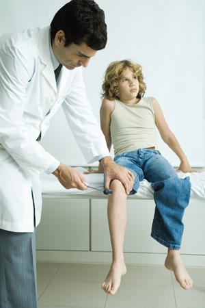 Male healthcare provider checking boy's reflexes