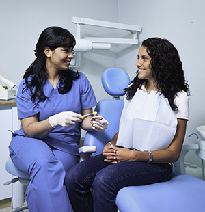 Dental healthcare provider talking to woman in exam room.