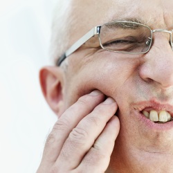 Man pressing into his jaw with a look of pain