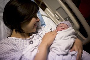 Woman in hospital bed with newborn baby.