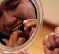 Reflejo de un espejo en el que se ve a una niña usando hilo dental